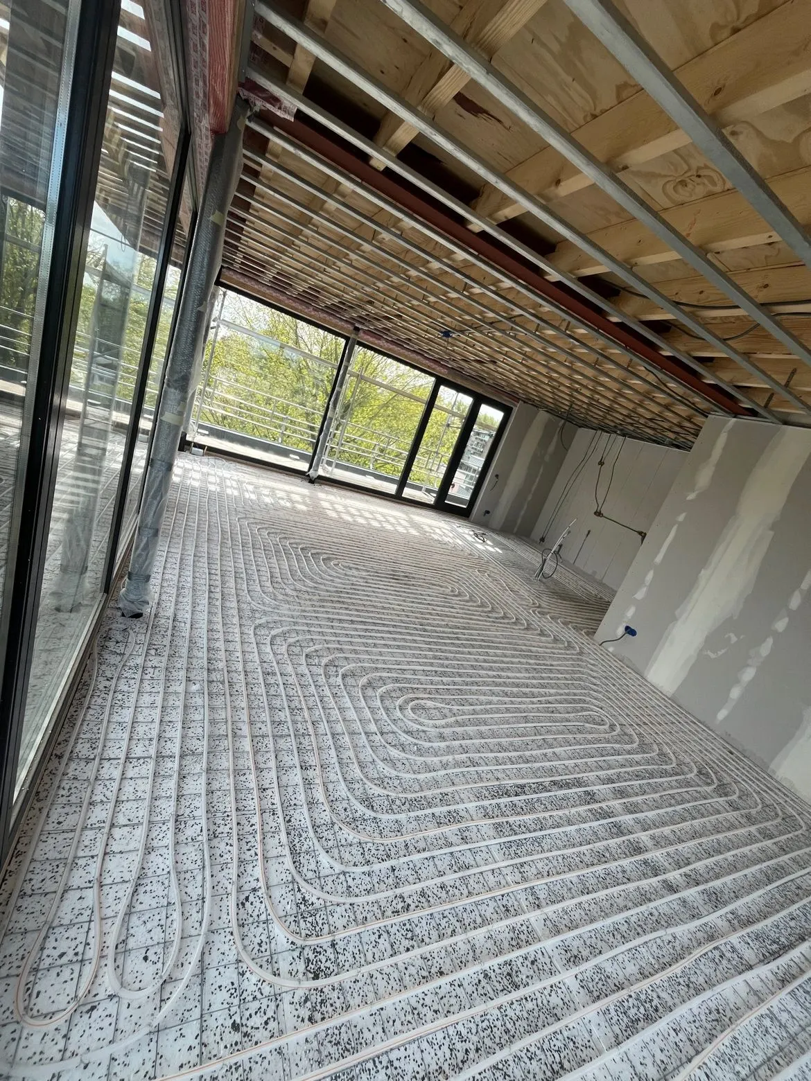 Woonkamer in aanbouw met de vloerverwarmingslussen op de isolatieplaten, voordat de dekvloer erover ging