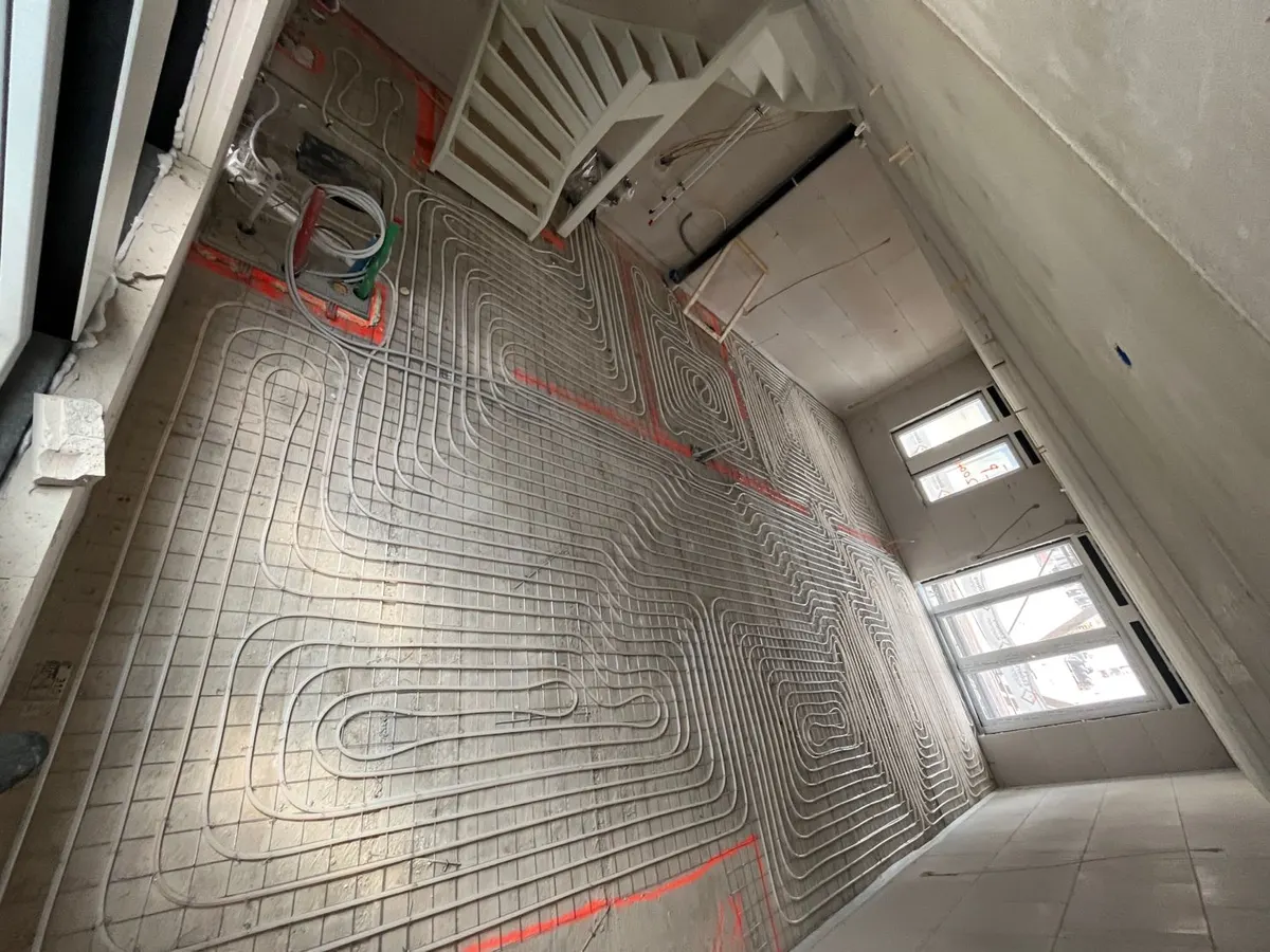 Leidingen op staalmat over de vloer van een seniorenwoning in het Hof van Ridderkerk, met de trap in beeld