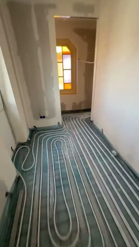 Gang met vloerverwarming, met daarachter een ruimte met een glas-in-loodraam