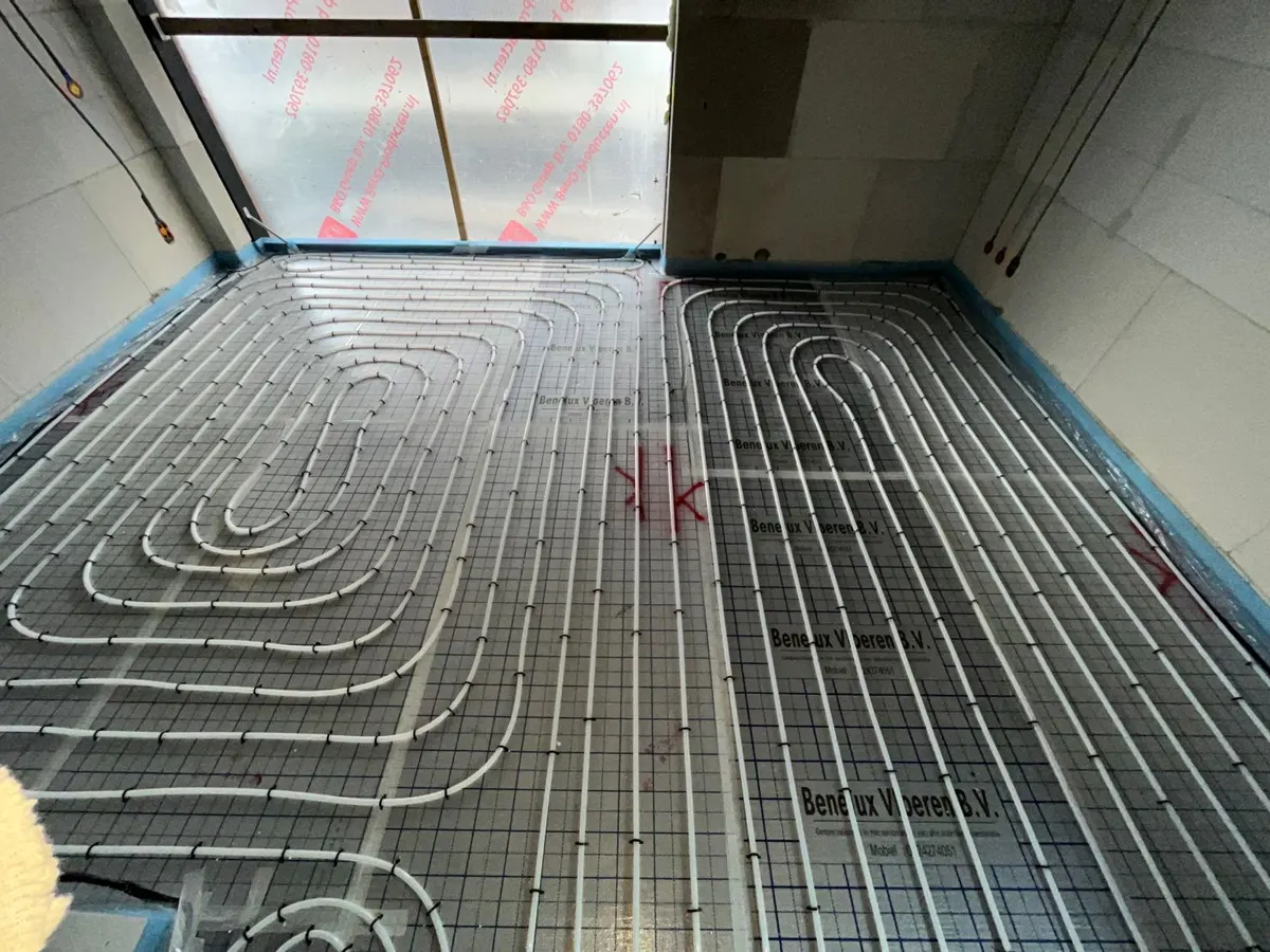 Twee lussen naast elkaar op staalmat, tot tegen de afgeplakte pui van een woning in Vrijlandt